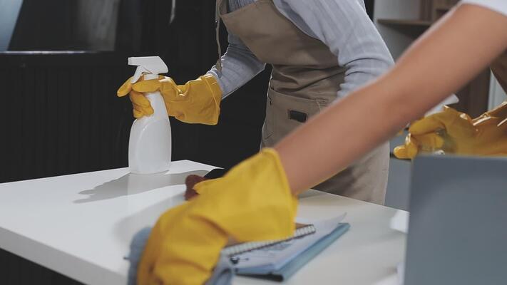 a-woman-wearing-yellow-gloves-and-apron-is-cleaning-a-table-free-video